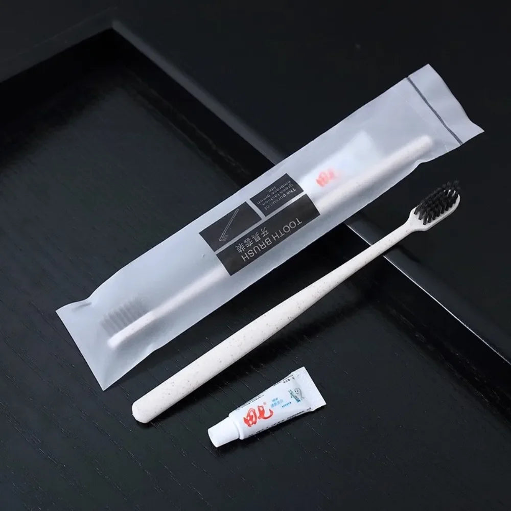 White toothbrush with packaging and a small tube of toothpaste on a dark surface